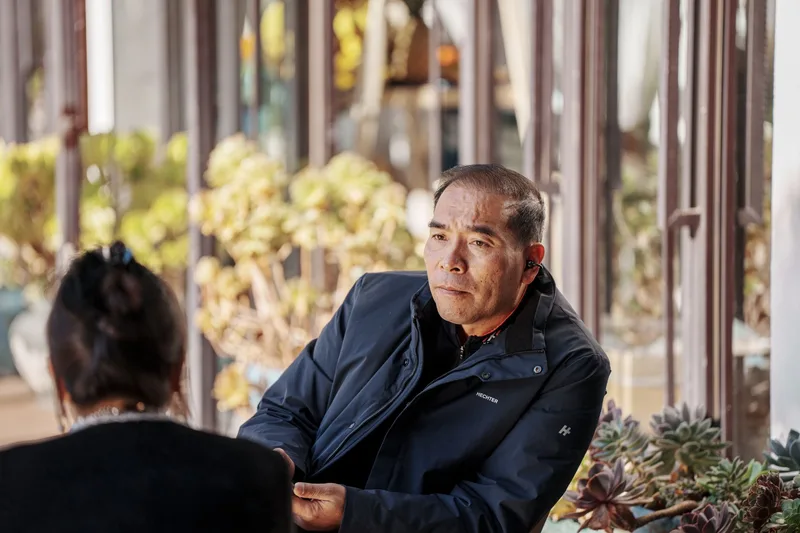 Two people having a relaxed conversation at an outdoor cafe, representing a customer discovery conversation used to validate a business idea