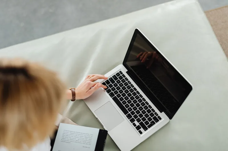 A person researching a business idea&rsquo;s market demand on a laptop, checking forums and competitor pages for existing demand signals