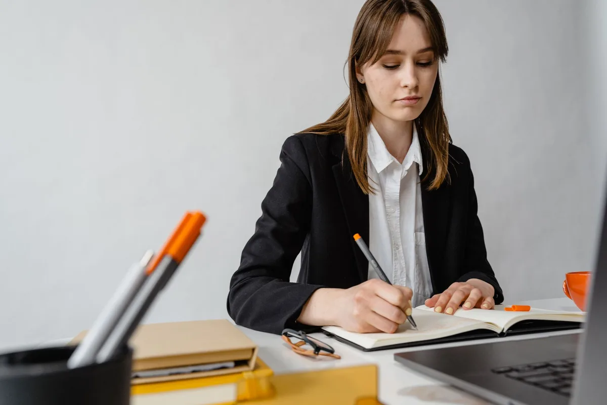 A solopreneur writing a one-sentence problem statement in a notebook at her desk before starting to validate a business idea