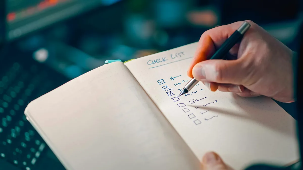 A structured scorecard notebook open on a desk next to a laptop with a blank product concept page