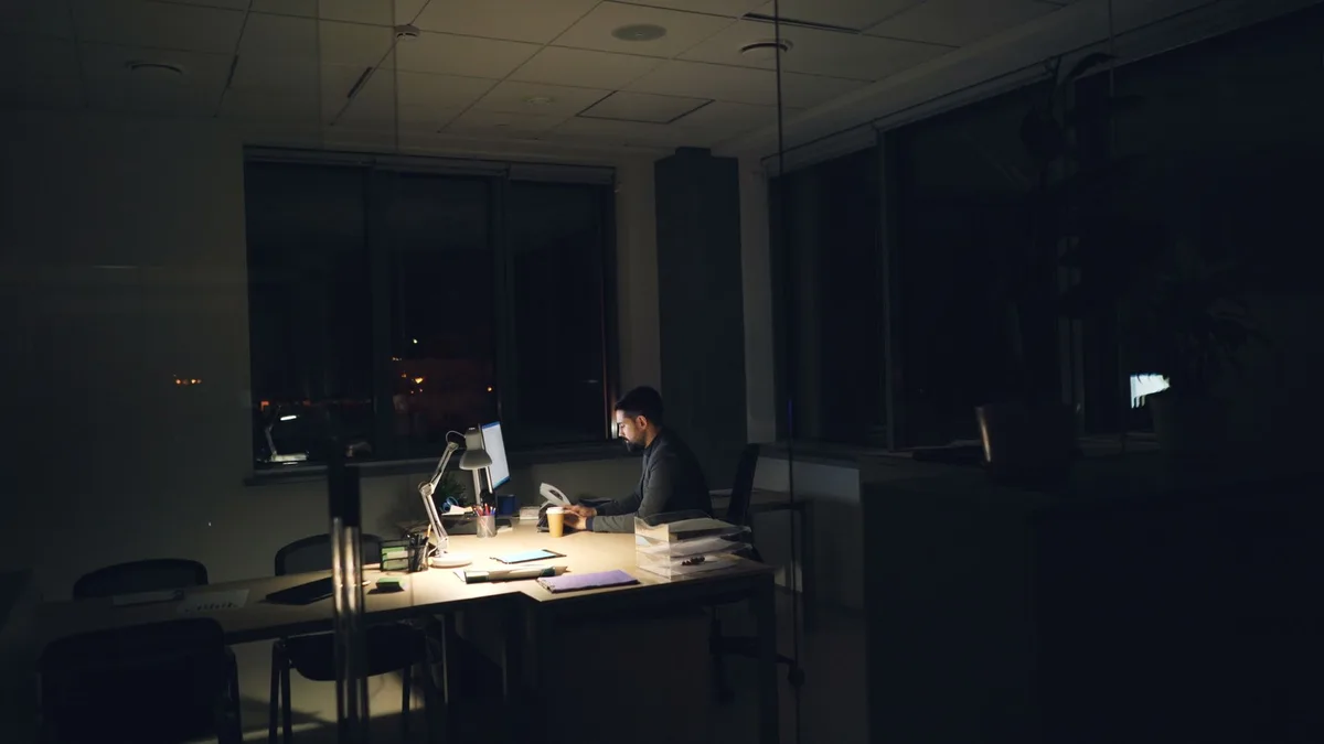 A solo founder sitting alone at a desk late at night, surrounded by sticky notes and sketched wireframes, representing isolated product decision-making with no outside challenge