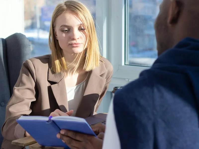 A person having a focused discovery conversation, listening carefully and taking notes on a problem