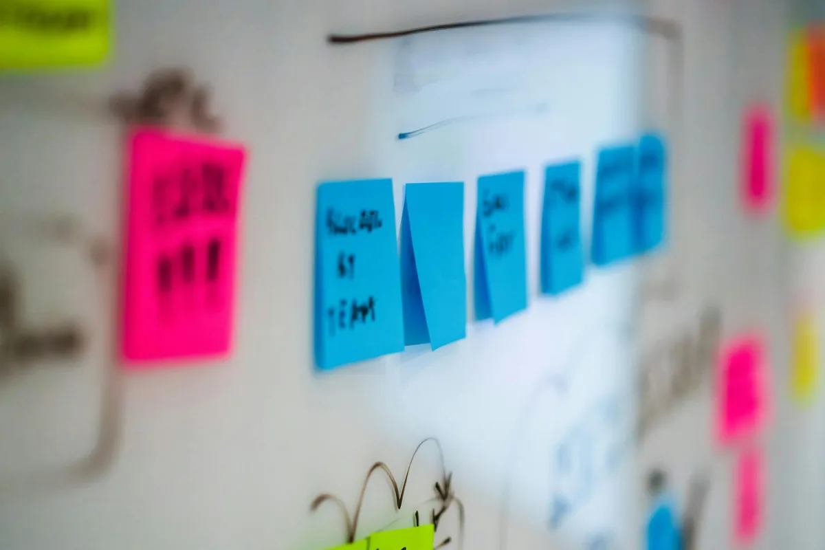 Two whiteboards side by side — one covered in sticky notes, customer quotes, and interview notes; the other blank except for a single box labeled &ldquo;Product v1.0&rdquo;